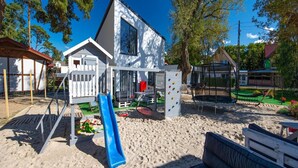 Ein Strandhaus mit Rutsche, Kletterwand und Sitzgelegenheit im Freien.