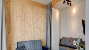 Ein modernes Wohnzimmer mit einer Holzwand, einem grauen Sofa, einem weißen Couchtisch und einer grauen Couch.
