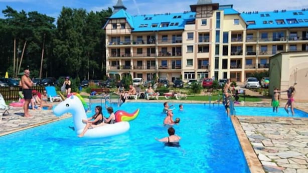 A swimming pool with inflatable toys and a hotel building in the background. - Apartment in Lukecin Near Baltic Sea (Dziwnów)