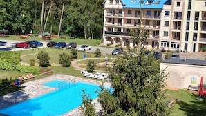 A hotel with a swimming pool, multiple balconies, and a parking area. - Apartment in Lukecin Near Baltic Sea (Dziwnów)