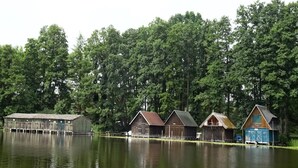 Eine Reihe von Holzhütten am Seeufer, umgeben von dichtem Wald.
