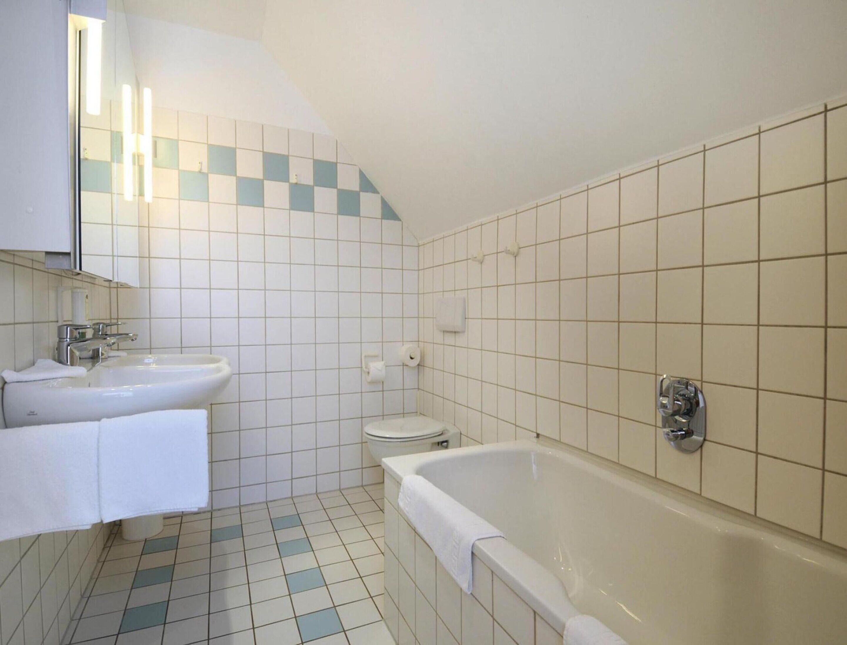 Un baño con lavamanos, inodoro y bañera.