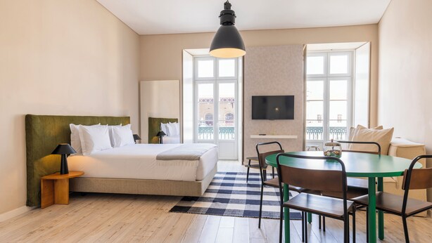 Una habitación de hotel moderna con una cama, un escritorio, un televisor y un balcón con vistas.