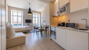 Una cocina moderna con microondas, cafetera y tostadora. Hay un comedor con mesa y sillas, y un sofá en la sala.