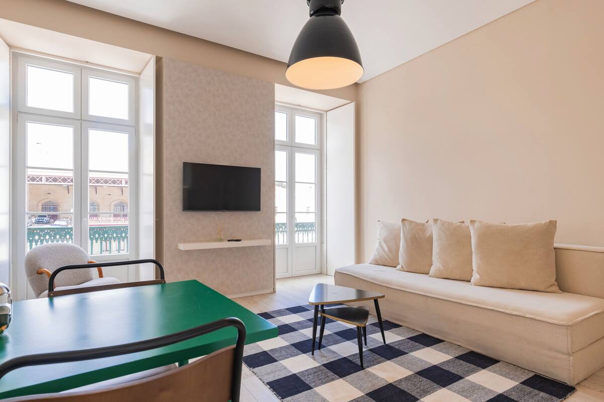 Una sala de estar moderna con un sofá, una mesa de comedor y un televisor montado en la pared.