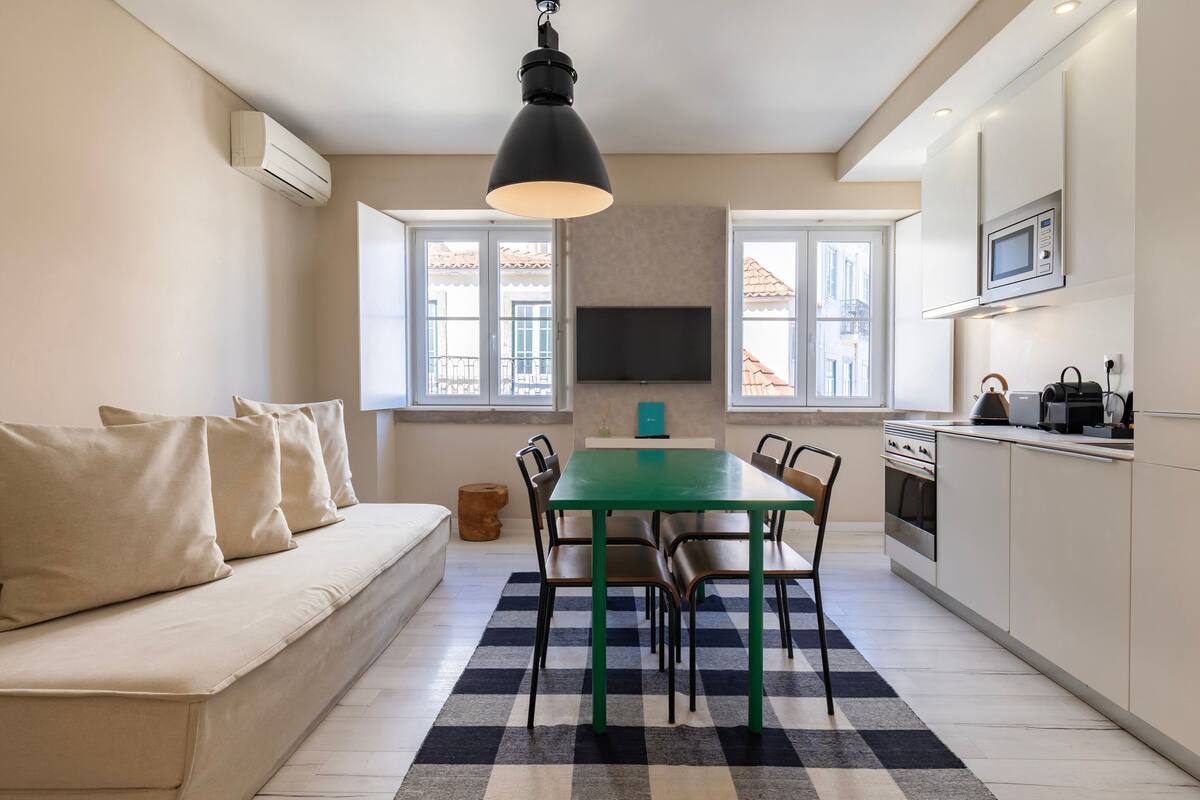 Una cocina moderna con una mesa de comedor, sillas y un televisor de pantalla plana encima.