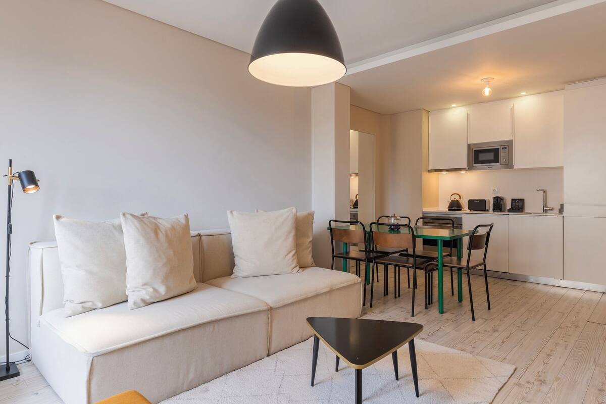 Una sala de estar moderna con un sofá, una mesa de centro y una zona de comedor con sillas y una mesa.