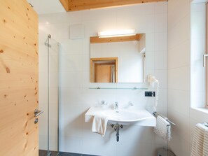 A modern bathroom with a glass shower enclosure, a white sink with a towel, and a mirror above the sink. - Apartments Home Apart Laudinella, See im Paznaun (See)