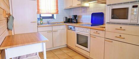A compact kitchen with a refrigerator, oven, microwave, and a coffee maker.