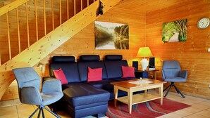 A wooden interior with a sofa, chairs, a table, a lamp, and two paintings. - Doppelhaushalfte in Hasselfelde (Oberharz am Brocken)
