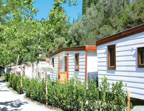 Una hilera de casas móviles blancas con detalles de madera, rodeada de follaje y árboles.