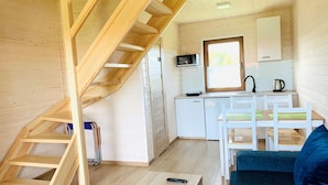 A compact wooden cabin with a kitchen area, a dining table with chairs, a staircase, and a sofa. - Two-story Holiday Homes Close to the sea (Mielno)