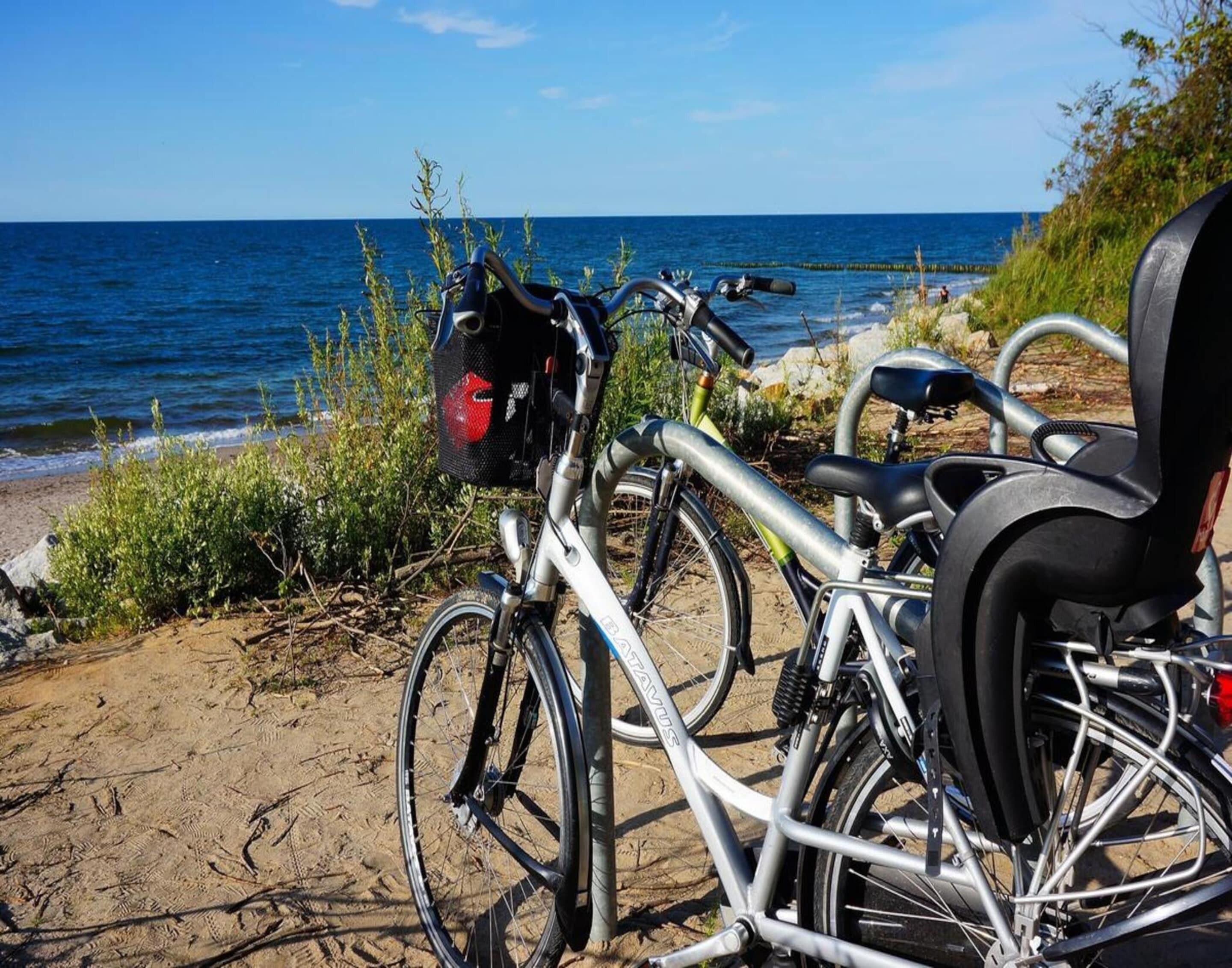 A bicycle parked on a sandy beach with a view of the ocean.