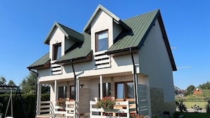 A two-story house with a balcony, a front porch with steps, and a small garden area. - Two-story Holiday Homes Close to the sea (Mielno)