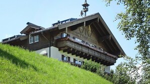 En traditionel schweizisk chalet med et stejlt tag, træbalkoner og vejrhane øverst.