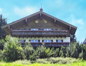 Edifício com várias andares e varandas, cercado por vegetação.