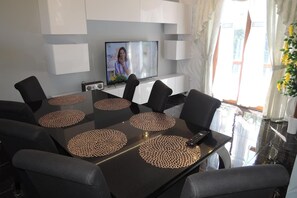 A modern dining area with a glass table, black chairs, and a television mounted on the wall. - Holiday Home Near Baltic Sea Swinoujscie (Swinoujscie)