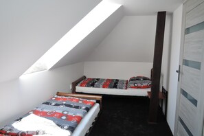 A small, sloped room with two beds, each with patterned bedding, a door with frosted glass panels, and a skylight. - Holiday Home Near Baltic Sea Swinoujscie (Swinoujscie)