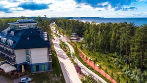 A modern hotel with a rooftop terrace, a landscaped pathway, and a view of the sea.