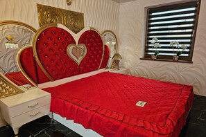 A bedroom with a red bedspread, a white bedside table, and a decorative headboard. - Holiday Home Near Baltic Sea Swinoujscie (Swinoujscie)