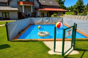 A swimming pool with a safety gate, surrounded by a grassy area and a building in the background. - Holiday Home Near Baltic Sea Swinoujscie (Swinoujscie)