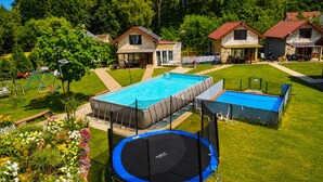 A residential area with a swimming pool, a trampoline, and stone houses with red roofs.