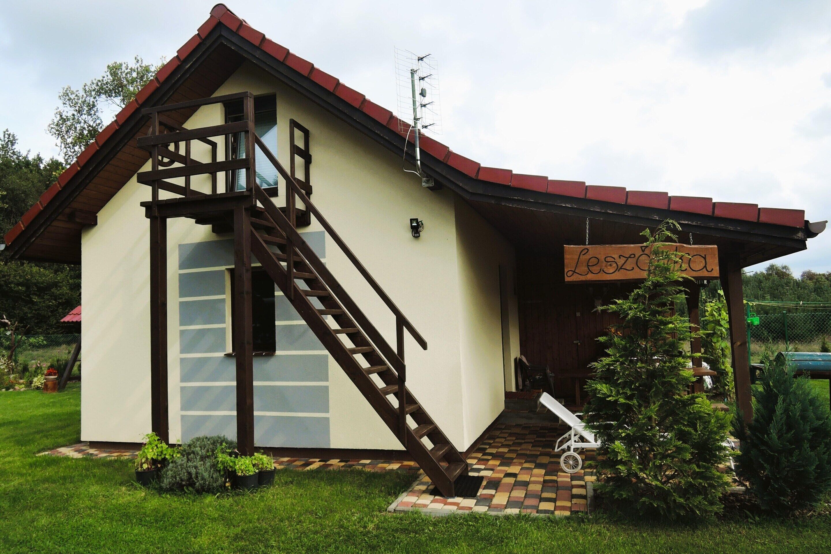A small building with a staircase leading to a balcony, a sign reading "Leszda," and a small Christmas tree.