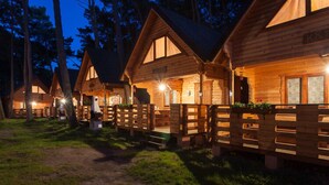 A row of wooden cabins with a porch and a small garden area in front. - Holiday Cottage in Pobierowo Near Baltic Beach (Rewal)