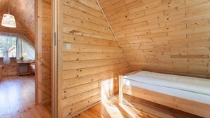 A wooden cabin with a loft bed, wooden walls, and a small kitchenette. - Holiday Cottage in Pobierowo Near Baltic Beach (Rewal)