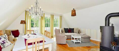 En hyggelig loftlejlighed med spiseplads, sofa, pejs og et stort vindue.