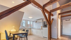 Eine moderne Küche mit weißen Schränken, einem Esstisch mit Stühlen und Holzbalken an der Decke.