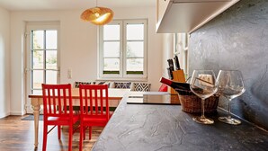 A kitchen with a marble countertop, red chairs, a wicker basket, and two wine glasses. - Ferienwohnung Franzl in Wendorf-bernsteinland (Kuhlen-Wendorf)