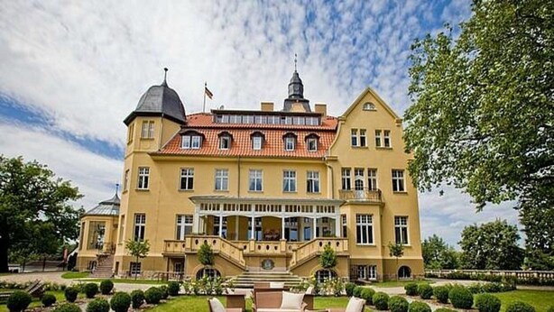 A large, yellow building with a red-tiled roof, a central staircase, and a well-maintained lawn with seating. - Ferienwohnung Franzl in Wendorf-bernsteinland (Kuhlen-Wendorf)