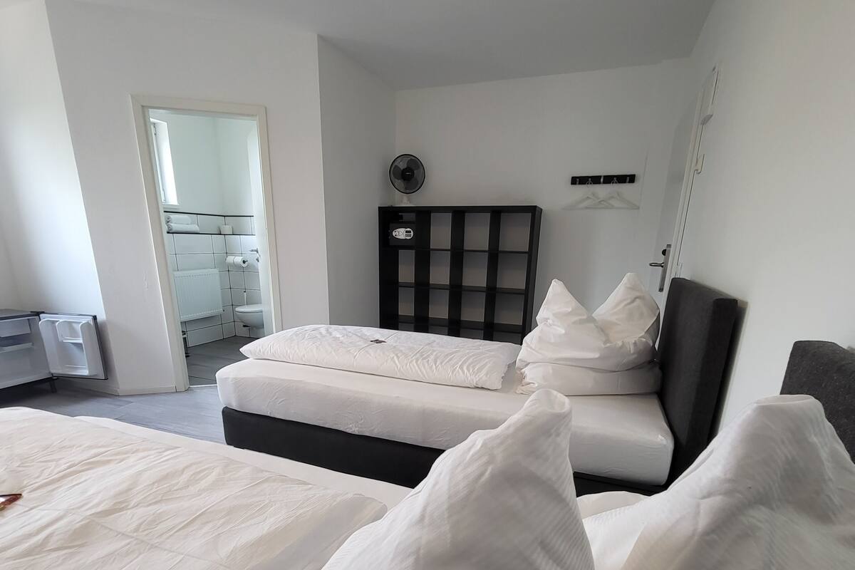 A hotel room with a bed, a bedside table, a mirror, and a wardrobe.