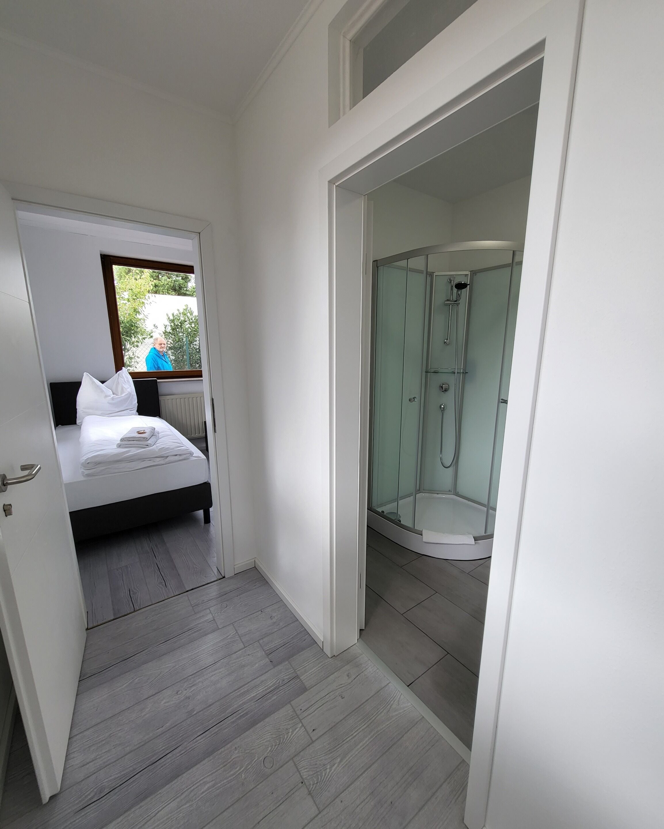 Ein modernes Hotelzimmer mit Bett, einer gläsernen Dusche und Blick ins Freie.