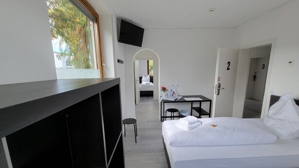 A hotel room with a bed, a desk, a TV, and a view of the outdoors.