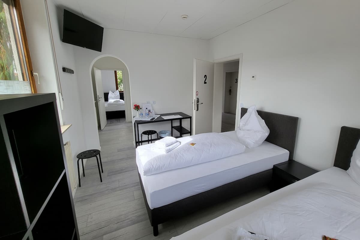 A hotel room with two beds, a desk, a TV, and a view of the outdoors.