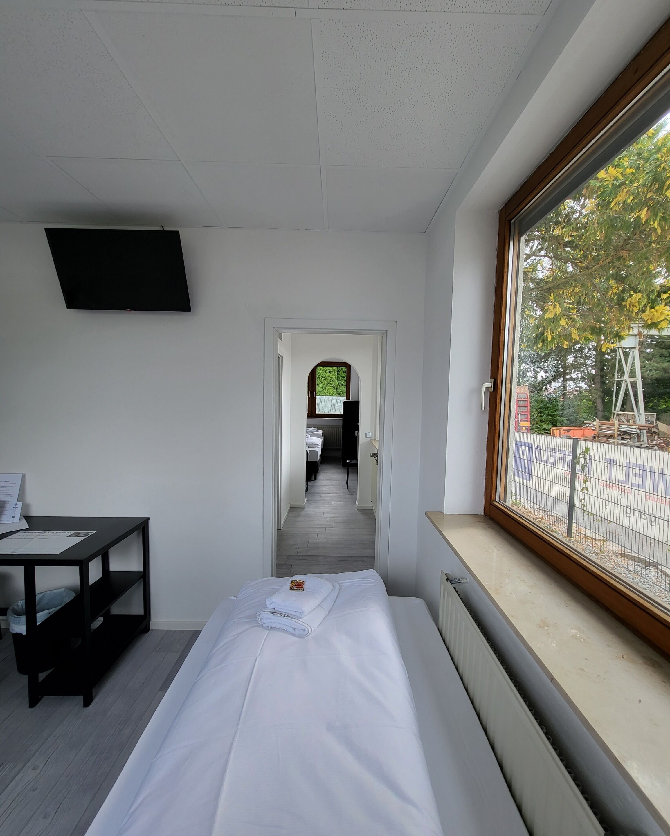 A hotel room with a bed, a desk, a TV, and a window with a view of the outside.