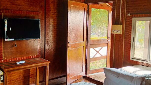 Une pièce en bois avec un lit, un bureau, une télévision et une porte donnant sur l’extérieur.