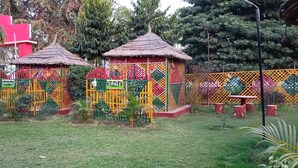Un jardin clos, comprenant deux petites constructions, peut-être des kiosques, et un banc.