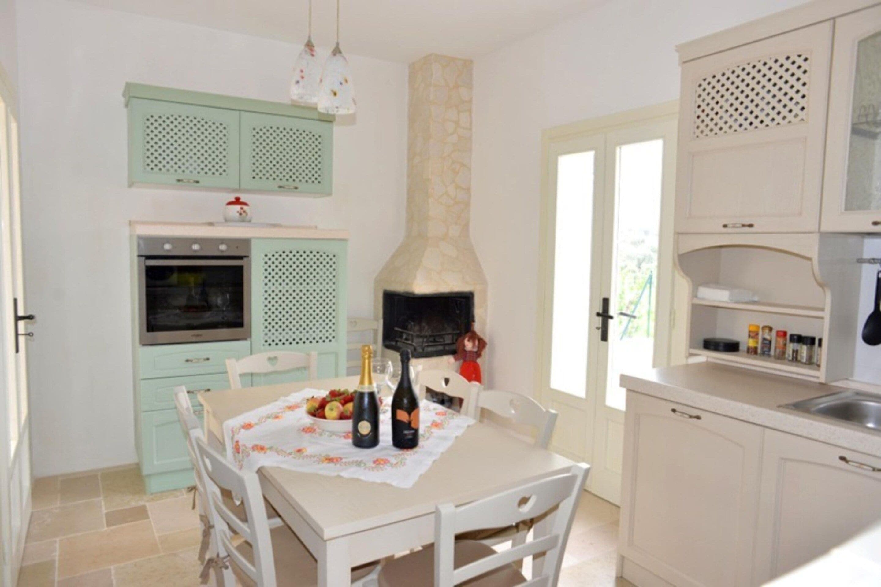 A kitchen with a dining table set for two, a pizza oven, and a window with a view.