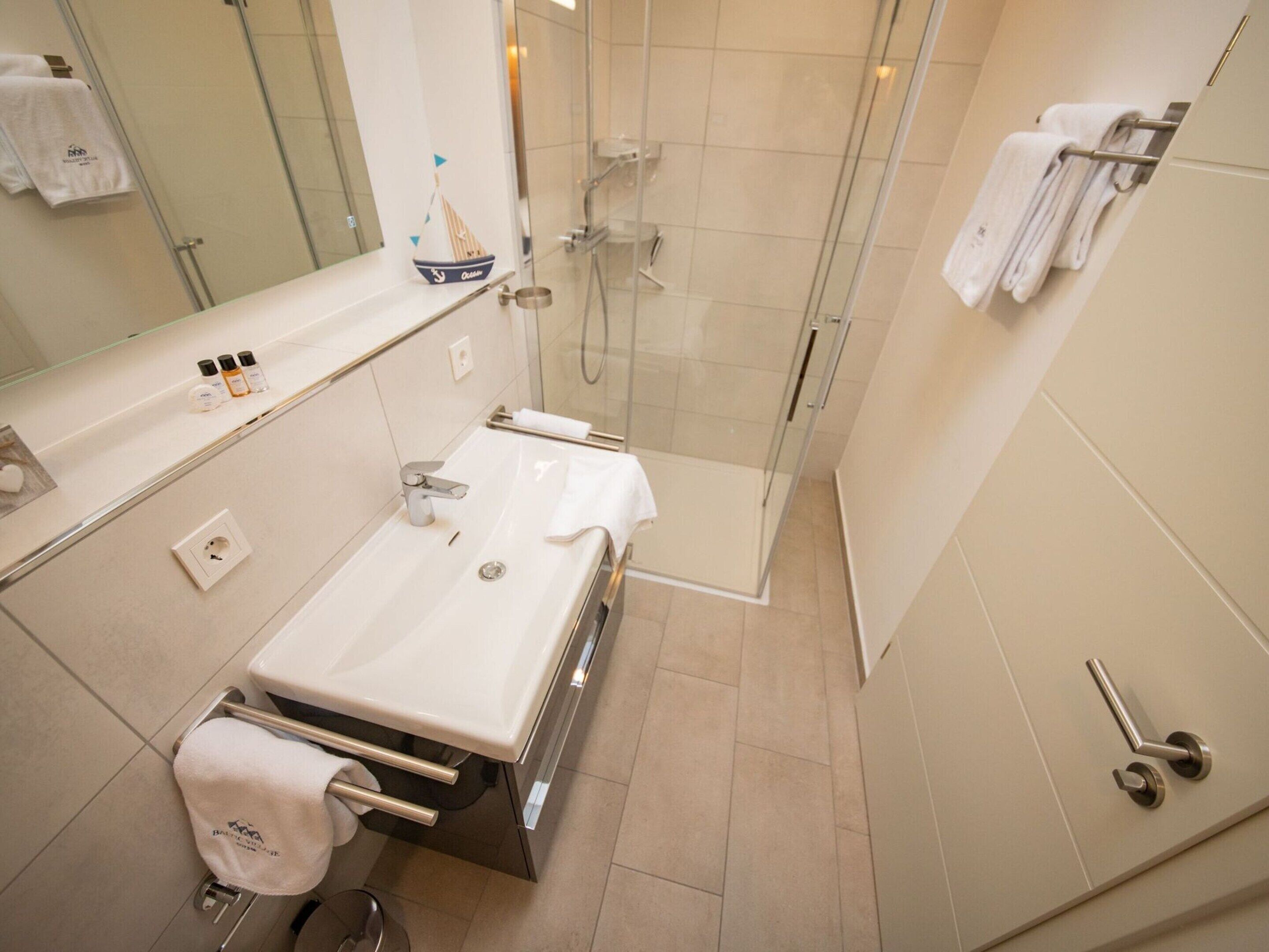 Une salle de bain moderne avec une douche à parois de verre, un lavabo blanc et un porte-serviettes.