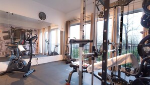 A gym with exercise equipment, large windows, and a mirror. - Ferienhaus in Damp Nahe Ostseestrand (Damp)