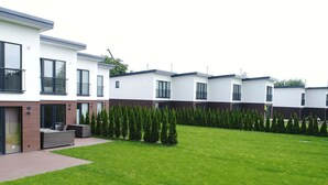 A modern residential building with a well-maintained lawn and neatly trimmed hedges. - Ferienhaus in Damp Nahe Ostseestrand (Damp)