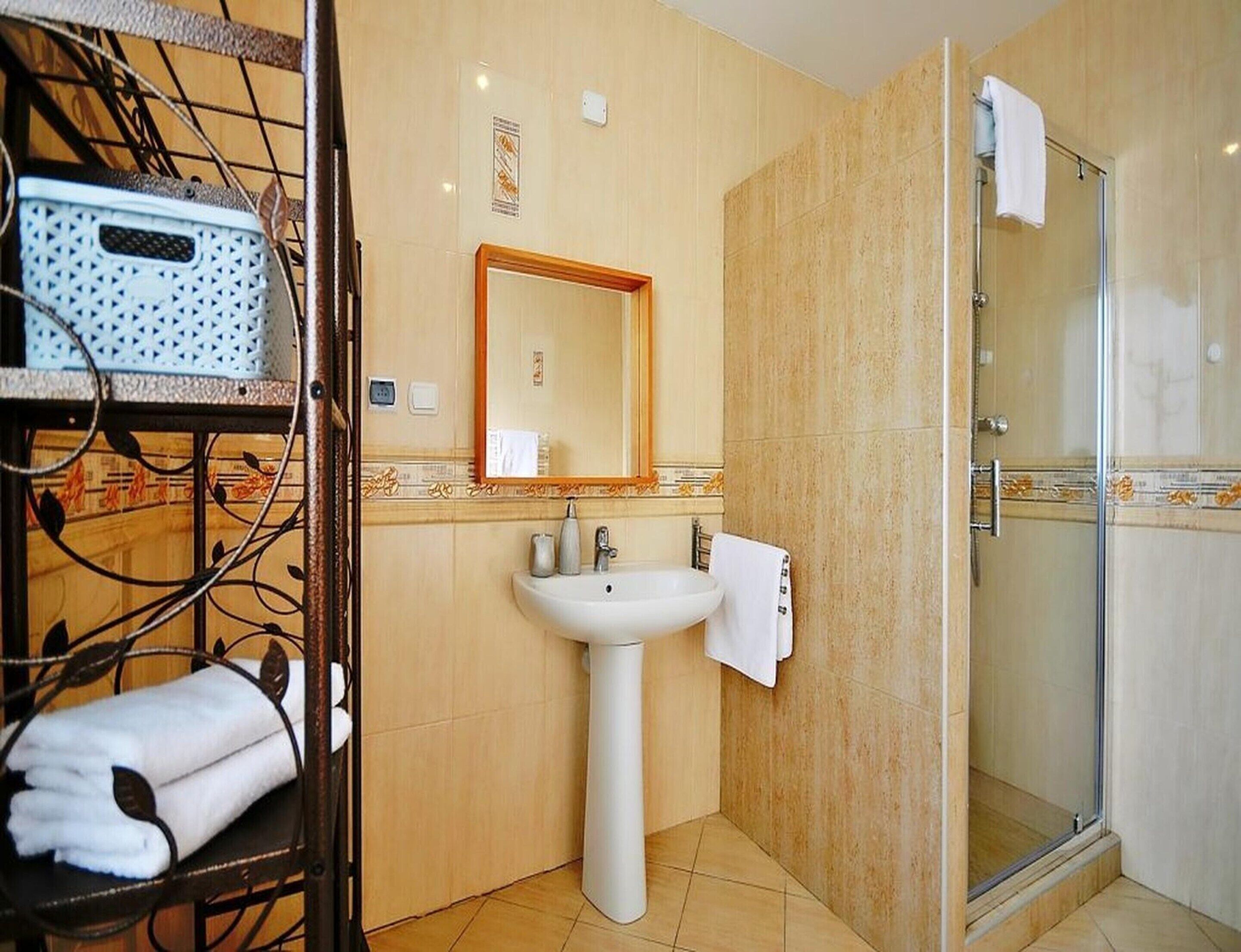 Un baño con lavamanos, espejo y ducha.