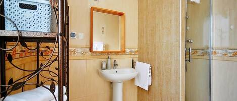 Un baño con lavamanos, espejo y ducha.