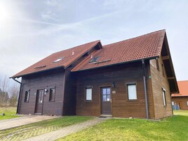 A two-story wooden building with a tiled roof, a front entrance, and a small porch area.