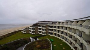 Un hôtel à plusieurs étages doté de balcons donnant sur une plage.