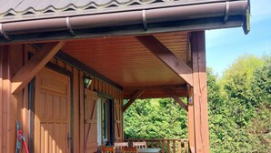 A wooden cabin with a covered porch, a dining table with chairs, and a wooden door. - Wooden House in Kolczewo Near Baltic Sea Beach (gmina Wolin)