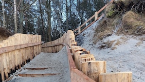 A wooden staircase with a sandy path leading up to a forested area. - Wooden House in Kolczewo Near Baltic Sea Beach (gmina Wolin)